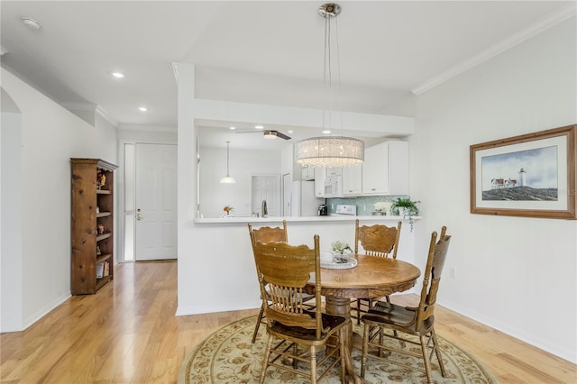 dining room with crown molding, sink, and light wood-type flooring