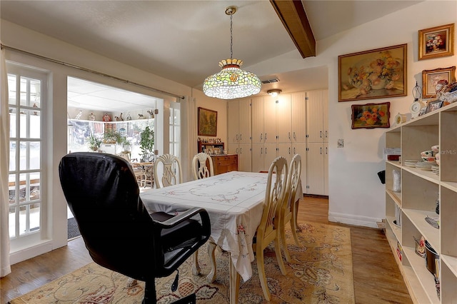 dining area with hardwood / wood-style flooring and vaulted ceiling with beams