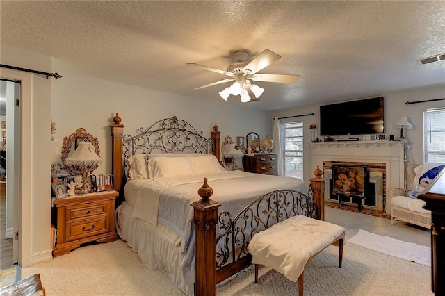 bedroom featuring ceiling fan, a barn door, a brick fireplace, and a textured ceiling