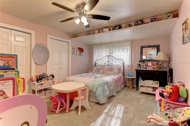 bedroom featuring two closets, light colored carpet, and ceiling fan