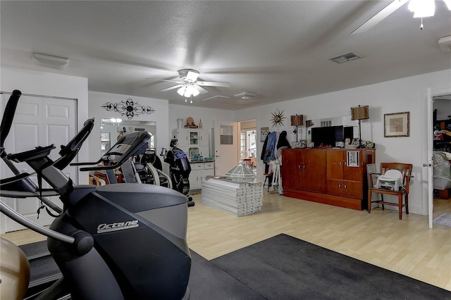 workout room featuring hardwood / wood-style flooring, a textured ceiling, and ceiling fan