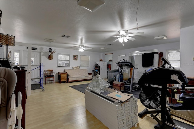 workout room featuring ceiling fan, a textured ceiling, and light hardwood / wood-style floors