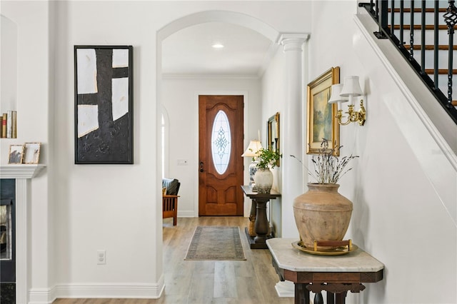 entryway featuring ornamental molding, light hardwood / wood-style flooring, and ornate columns