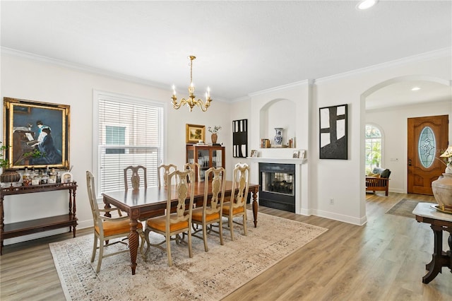 dining space with ornamental molding, a chandelier, and light hardwood / wood-style floors