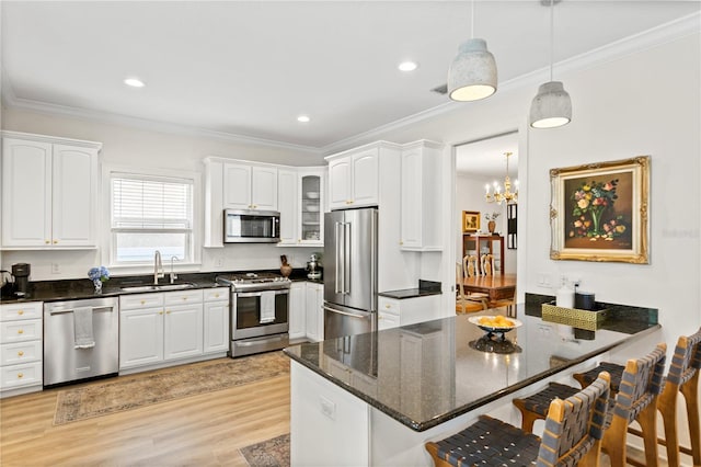 kitchen featuring hanging light fixtures, ornamental molding, appliances with stainless steel finishes, and white cabinets