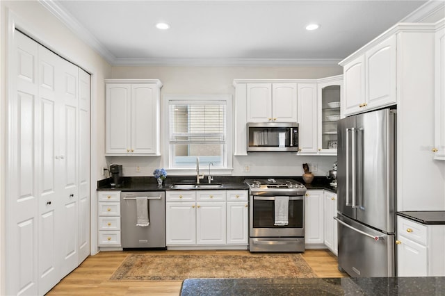 kitchen with stainless steel appliances, white cabinetry, sink, and light wood-type flooring