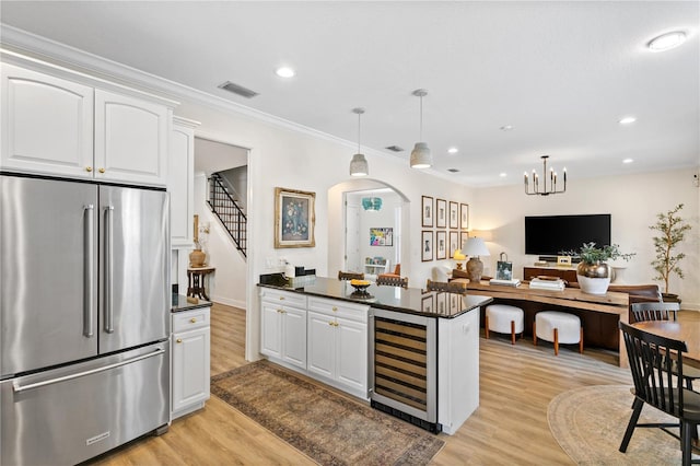 kitchen with high quality fridge, wine cooler, white cabinets, and decorative light fixtures