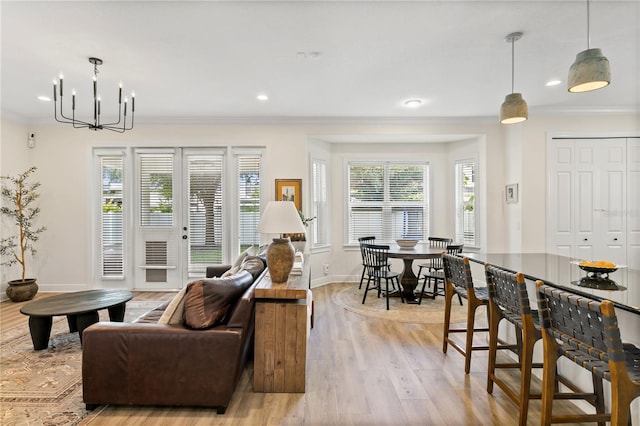 living room featuring french doors, ornamental molding, a chandelier, and light hardwood / wood-style floors