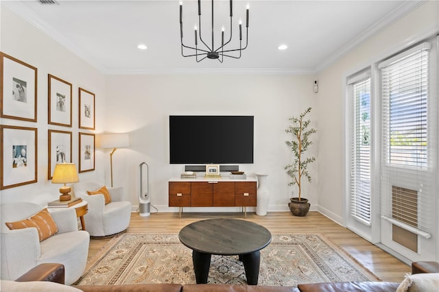 living room with crown molding, a notable chandelier, and light hardwood / wood-style floors