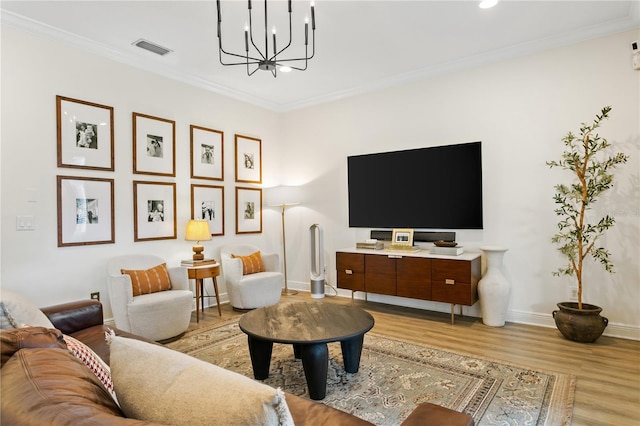 living room featuring ornamental molding, a notable chandelier, and light hardwood / wood-style flooring