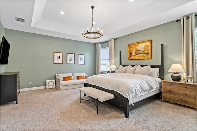 carpeted bedroom featuring a tray ceiling and a notable chandelier