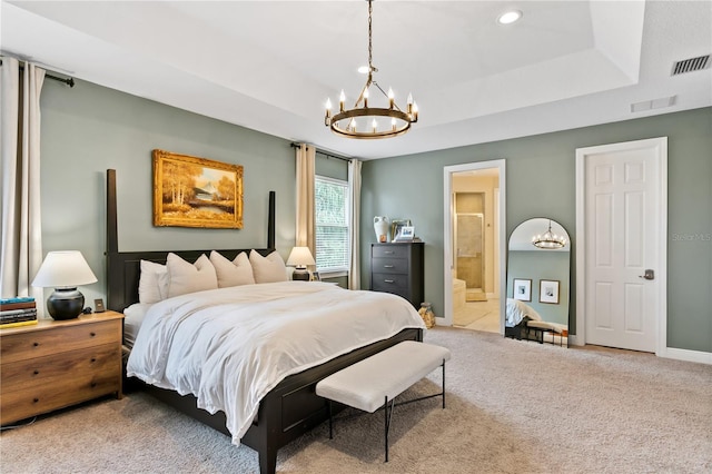 bedroom with ensuite bathroom, carpet flooring, an inviting chandelier, and a tray ceiling