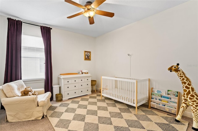 bedroom featuring a nursery area and ceiling fan