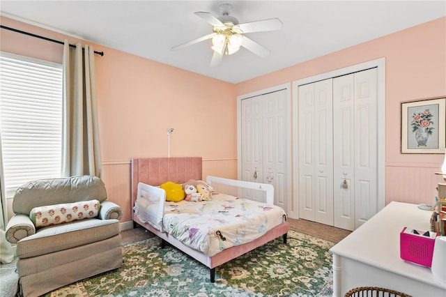 bedroom featuring carpet floors, two closets, and ceiling fan