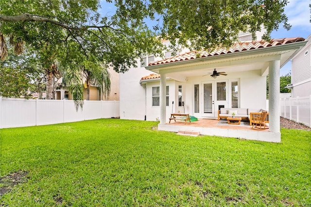 rear view of house featuring ceiling fan, a patio, outdoor lounge area, and a lawn