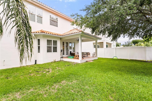 rear view of property with ceiling fan, a yard, and a patio