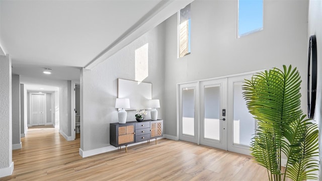 foyer entrance with light hardwood / wood-style flooring, french doors, and a high ceiling