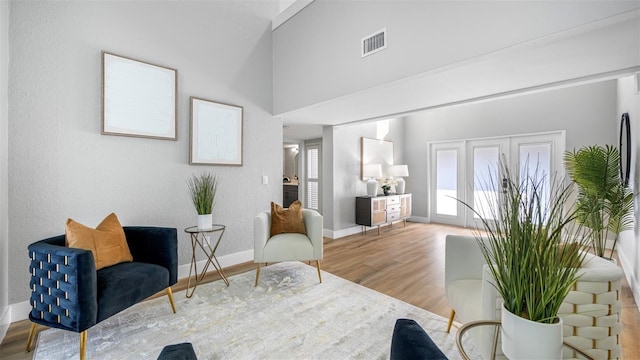 living area with a towering ceiling and hardwood / wood-style floors