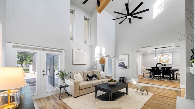 living room featuring hardwood / wood-style flooring, ceiling fan, beam ceiling, a high ceiling, and french doors