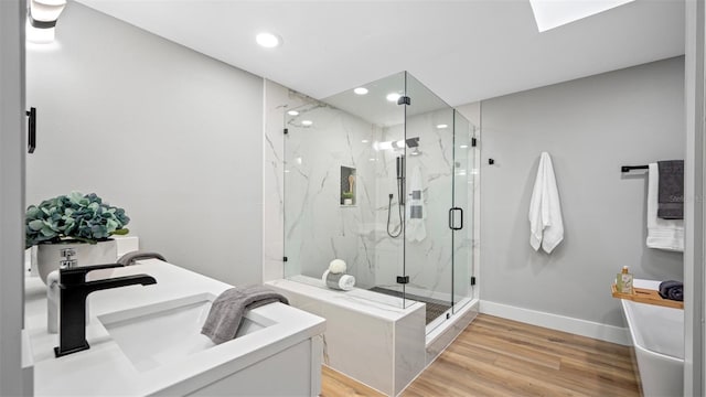 bathroom featuring a skylight, wood-type flooring, vanity, and a shower with shower door