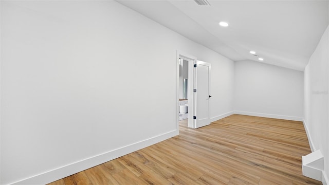 spare room featuring lofted ceiling and light hardwood / wood-style flooring