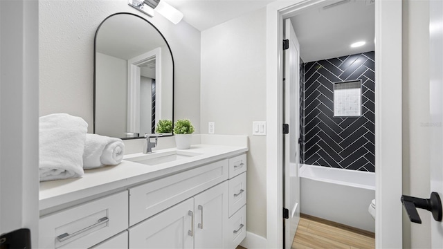 full bathroom with vanity, tiled shower / bath combo, wood-type flooring, and toilet