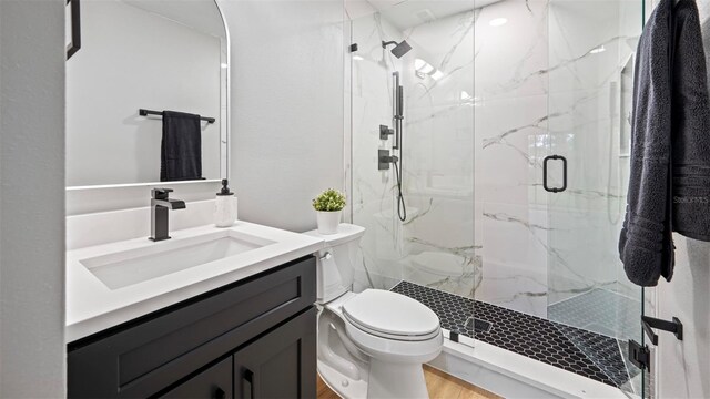 bathroom featuring vanity, an enclosed shower, wood-type flooring, and toilet