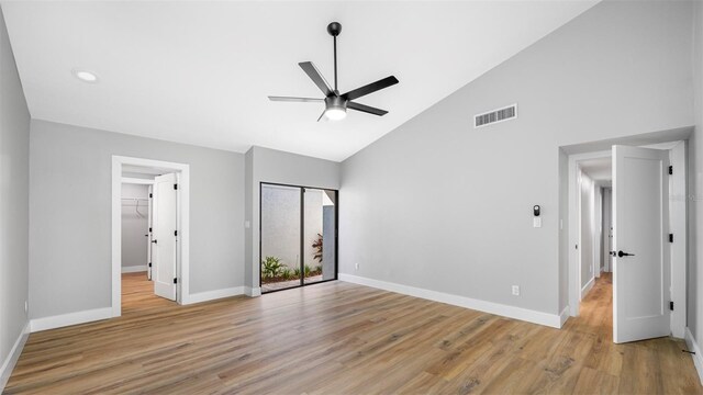 unfurnished bedroom featuring ceiling fan, high vaulted ceiling, a spacious closet, and light wood-type flooring