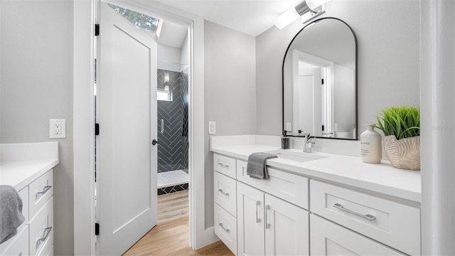 bathroom featuring tiled shower, vanity, and hardwood / wood-style floors