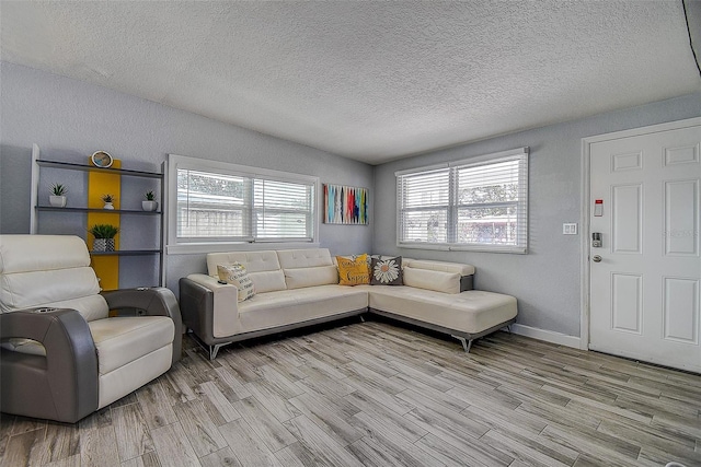 living room with lofted ceiling, a textured ceiling, a healthy amount of sunlight, and light wood-type flooring