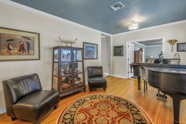 living area with ornamental molding and wood-type flooring