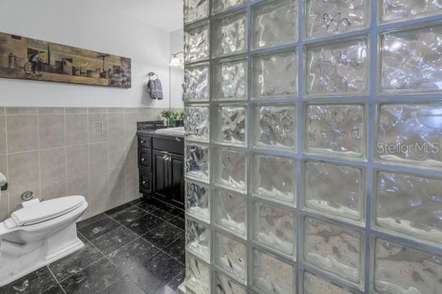 bathroom with vanity, toilet, and tile walls