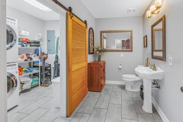 bathroom featuring electric panel, stacked washer and clothes dryer, and toilet