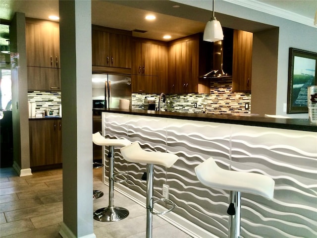 bar featuring pendant lighting, decorative backsplash, ornamental molding, and wall chimney exhaust hood