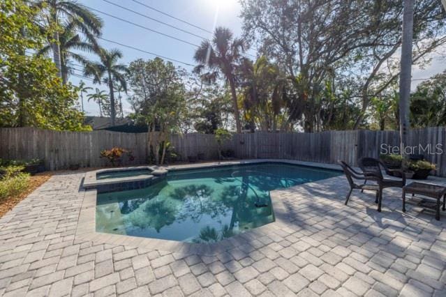 view of swimming pool featuring a patio and an in ground hot tub