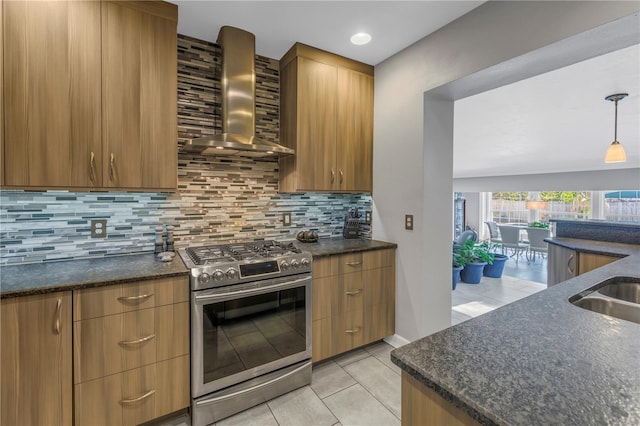 kitchen featuring wall chimney exhaust hood, gas range, tasteful backsplash, light tile patterned floors, and pendant lighting