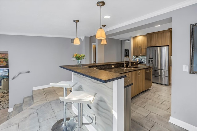 kitchen with a breakfast bar, sink, crown molding, decorative light fixtures, and stainless steel appliances