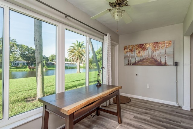 dining area with hardwood / wood-style flooring, a water view, and ceiling fan