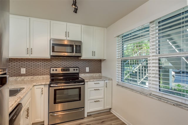 kitchen with white cabinetry, appliances with stainless steel finishes, light stone counters, and decorative backsplash