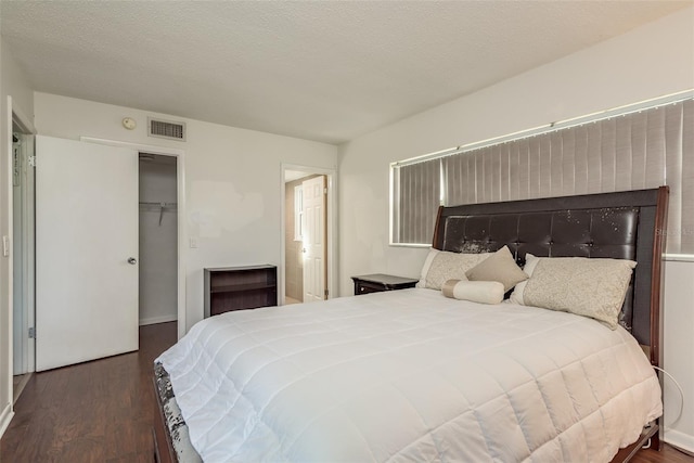 bedroom featuring a textured ceiling, dark hardwood / wood-style flooring, and a closet