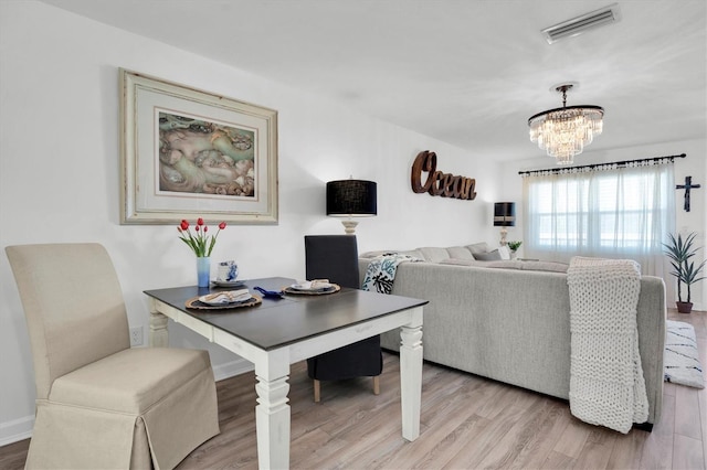 dining area featuring light hardwood / wood-style flooring and a notable chandelier