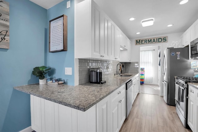 kitchen featuring sink, white cabinetry, appliances with stainless steel finishes, light hardwood / wood-style floors, and backsplash