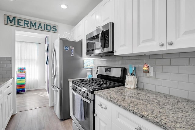 kitchen featuring white cabinetry, stainless steel appliances, and light stone counters