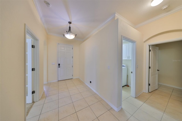 foyer with washer / clothes dryer, crown molding, and light tile patterned floors