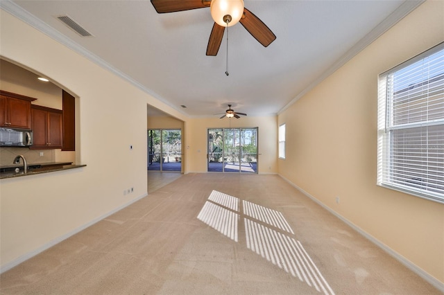 unfurnished living room featuring light colored carpet, ornamental molding, and sink