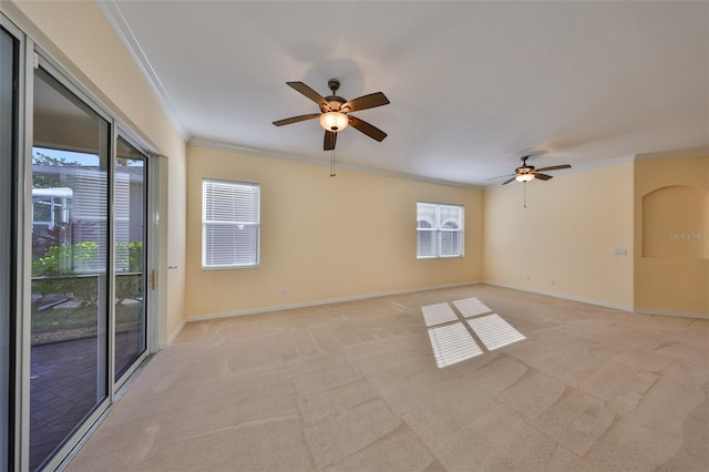 carpeted spare room featuring crown molding, ceiling fan, and a wealth of natural light