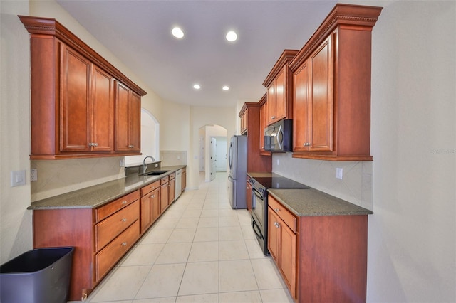 kitchen featuring light tile patterned flooring, sink, dark stone countertops, appliances with stainless steel finishes, and decorative backsplash