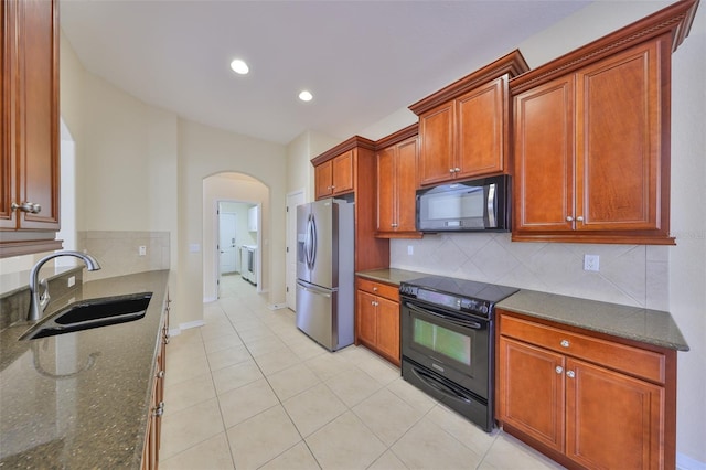 kitchen featuring sink, dark stone countertops, backsplash, stainless steel fridge with ice dispenser, and black range with electric cooktop