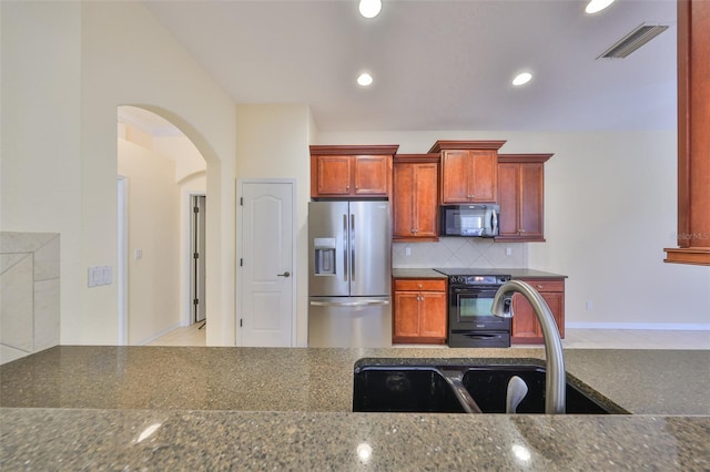 kitchen featuring tasteful backsplash, sink, black appliances, and dark stone countertops