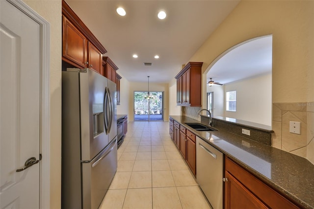 kitchen with pendant lighting, sink, light tile patterned floors, appliances with stainless steel finishes, and dark stone countertops